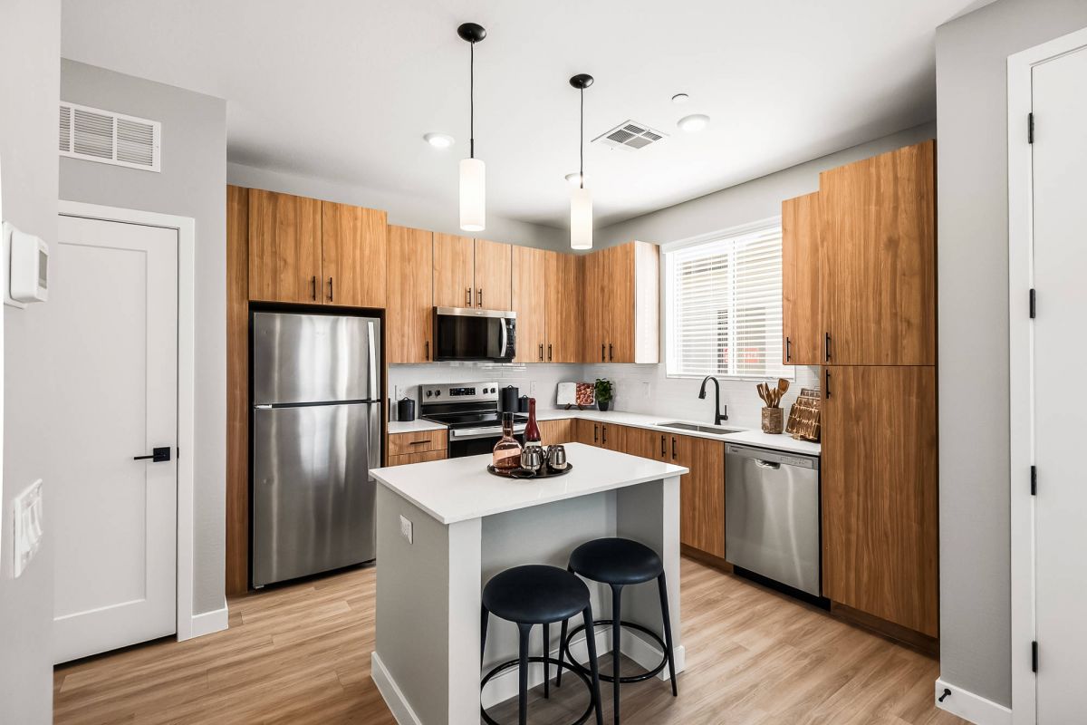 Sonita Goodyear home kitchen with wood cabinets, stainless steel appliances, an island, and pendant lights.